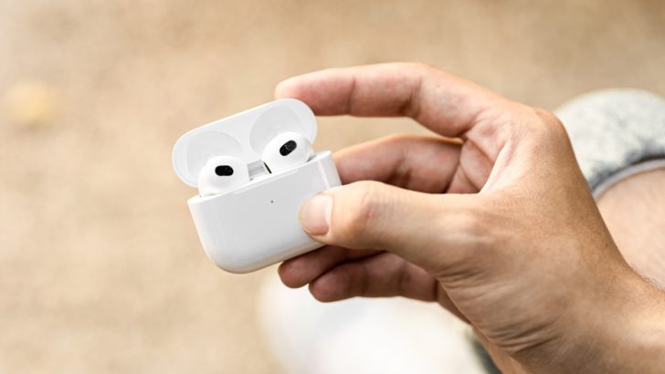 Photo of person holding airpods in case with lid open