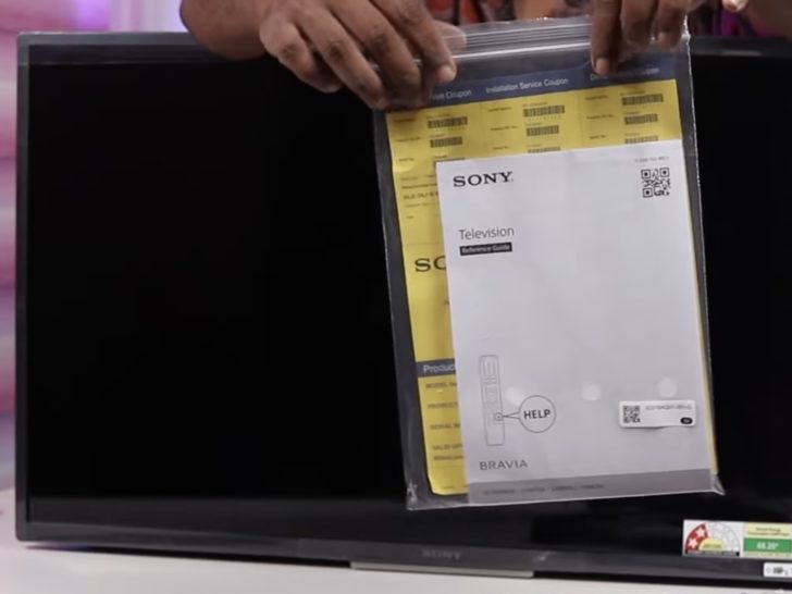 Photo of person holding a sony tv manual in front of sony tv screen
