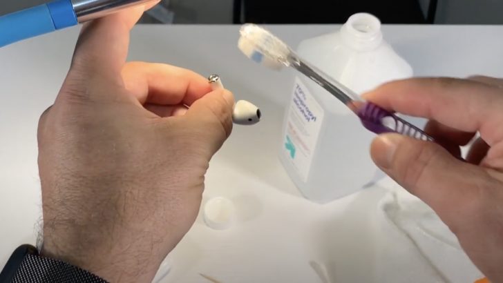 Photo of person cleaning airpods stem using toothbrush