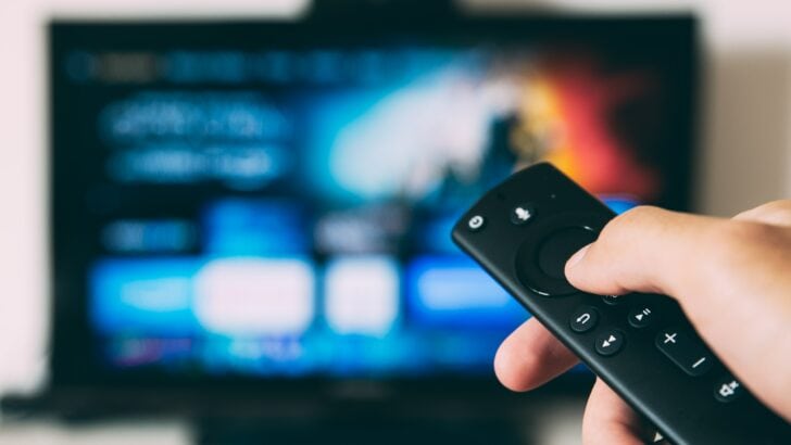 Photo of person holding samsung tv remote with samsung tv on the background