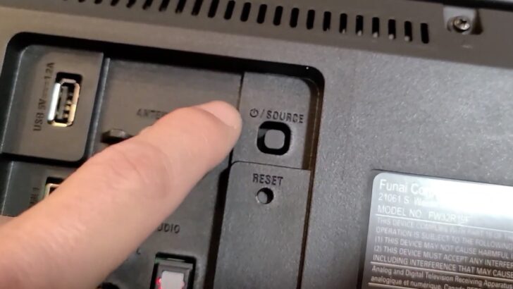 Photo of person locating the power button on the back of sanyo roku tv
