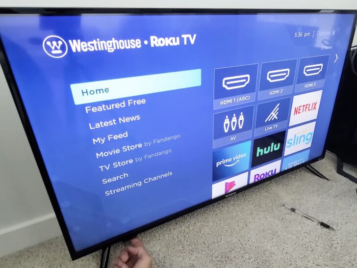 Photo of person pressing the power button on westinghouse roku tv