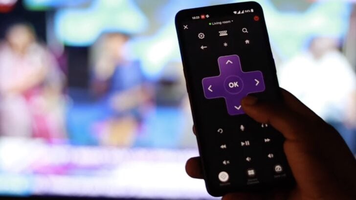 Photo of person using roku app in smartphone as roku tv remote