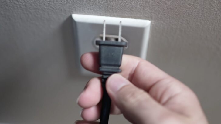 Photo of person unplugging samsung tv from the power outlet