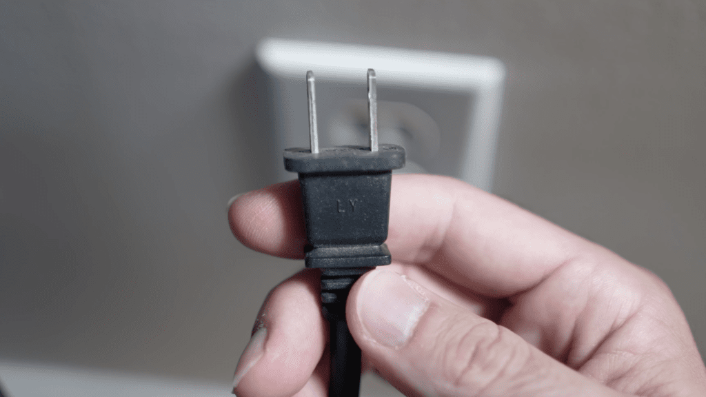 Photo of a person unplugging a Hisense TV from the wall outlet