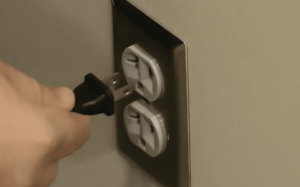 Photo of a person unplugging a Vizio TV power cord from a wall outlet