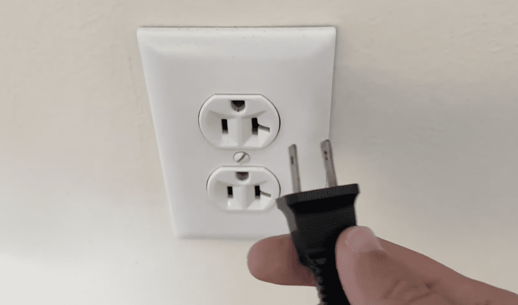 Photo of a person unplugging an LG TV power cord from a wall outlet
