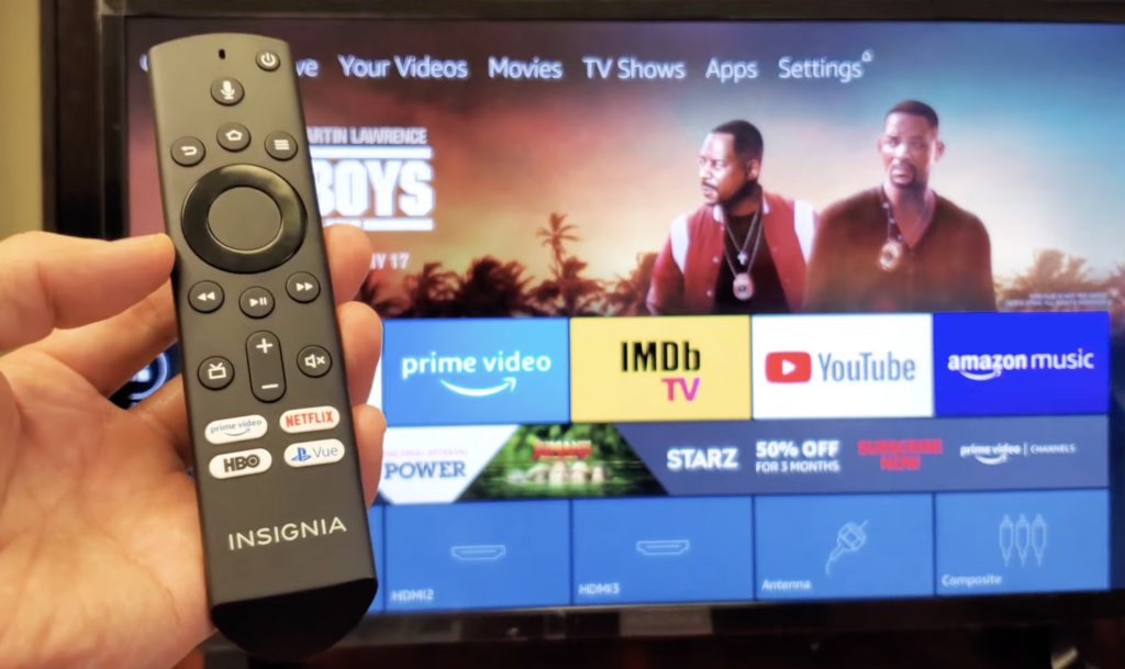 Photo of someone holding an Insignia remote in front of an Insignia TV