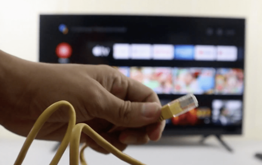 Photo of a person connecting a TV to a Wi-Fi router via ethernet cable