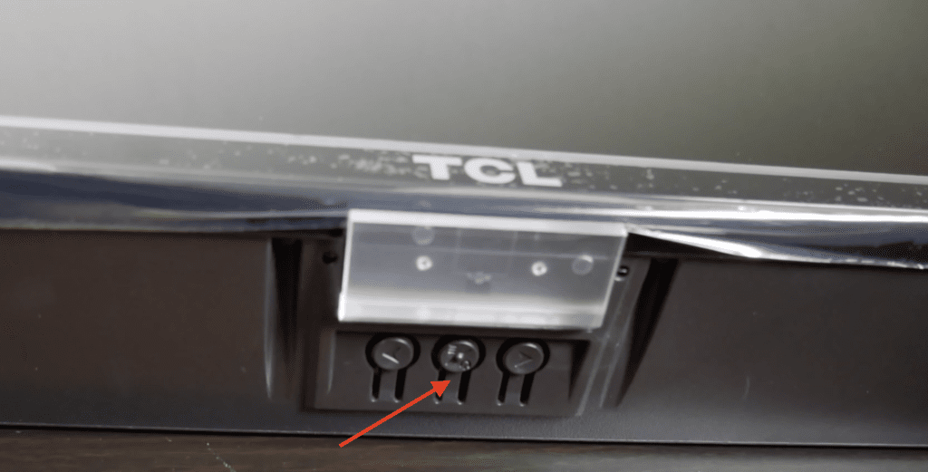 Photo of the power button at the middle underside of a TCL Roku TV