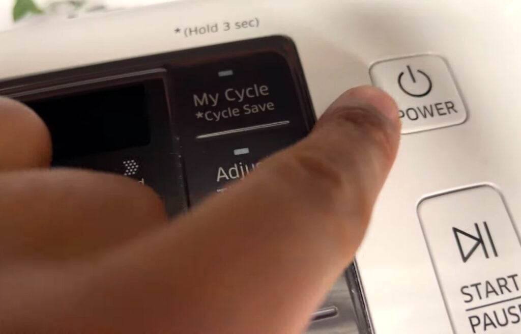 a finger pointing on the power button of a Samsung dryer