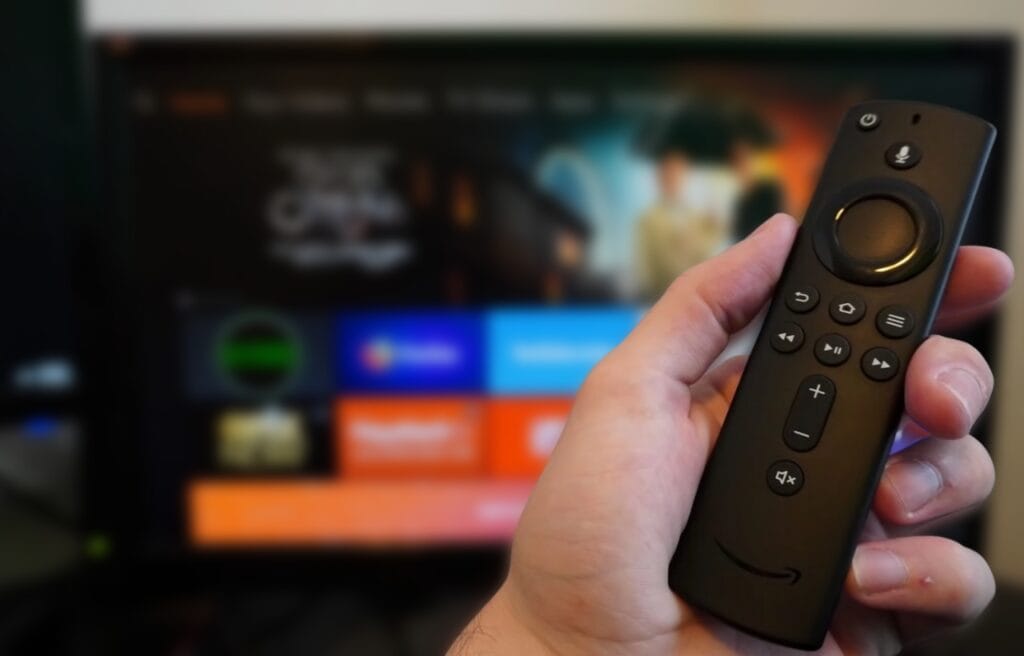 holding a Firestick remote with TV screen on the background