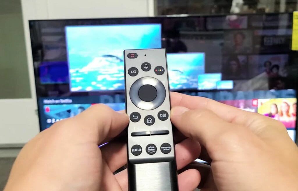 Holding a Samsung remote and showing the back and play button