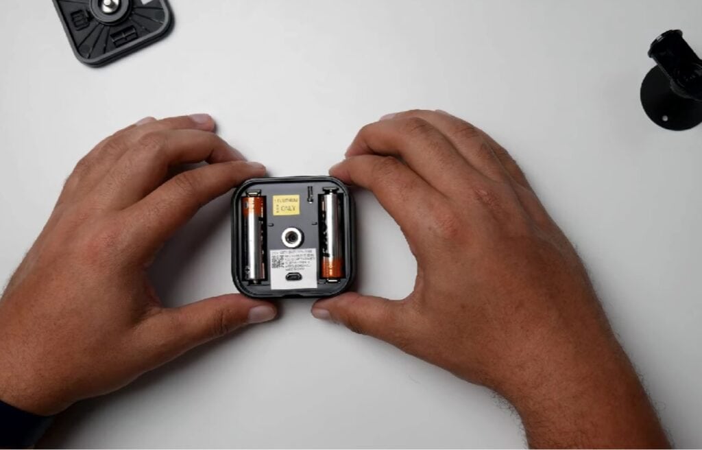 hand holding an opened Blink camera showing its batteries