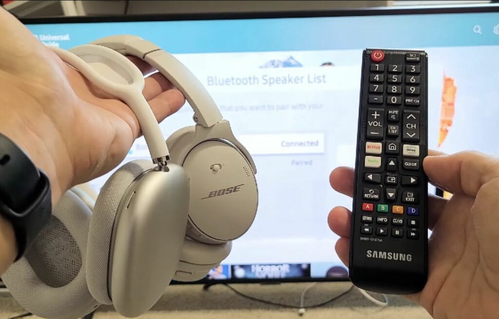 holding a wireless headphones and a Samsung remote