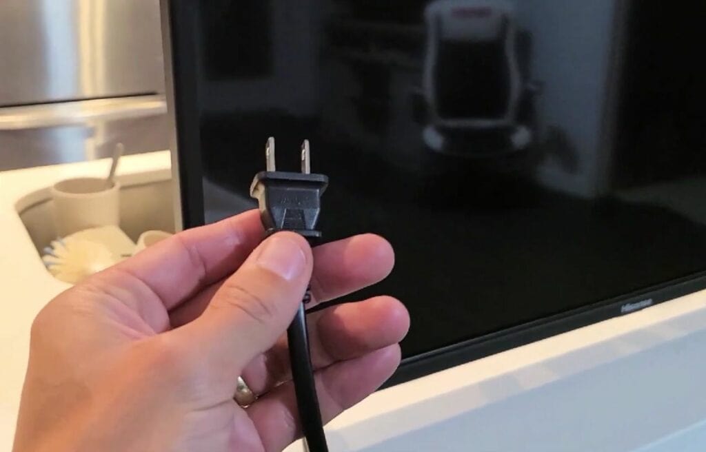 hand holding a plug of a Hisense TV