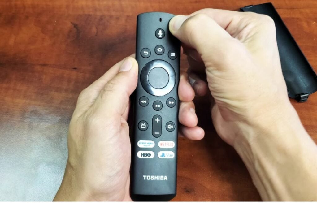 man pressing the power button on a Toshiba fire remote